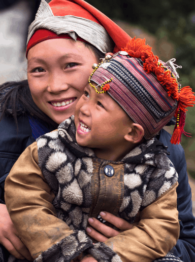 A village woman sits with a smiling child.